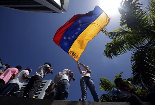 An anti-government student waves a Venezuelan flag during a protest rally in Caracas on February 16, 2014. Supporters and opponents of Venezuela's leftist government have been staging rival rallies amid spiraling discontent at the country's stubborn inflation and shortage of basic goods. Two anti-government protesters and a pro-Maduro demonstrator died in a rally early this week.    AFP PHOTO/JUAN BARRETO