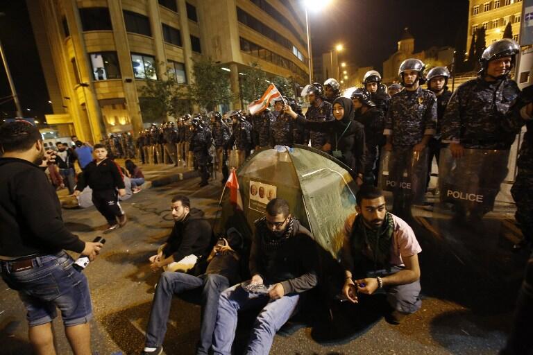 Lebanese protesters sit in protest in front of the government headquarters during a demonstration against the on-going trash crisis and government corruption, in downtown Beirut, on March 12, 2016. Lebanon said it would reopen new landfills as a temporary solution to an eight-month rubbish crisis as thousands of people demonstrated in Beirut against the waste pile-up. Rubbish has piled up on beaches, mountain forests and river beds across Lebanon since the closure in July of the country's largest landfill at Naameh, just south of Beirut. Since then, numerous proposals by the government to export the trash or treat it in Lebanon have fallen flat. / AFP / ANWAR AMRO