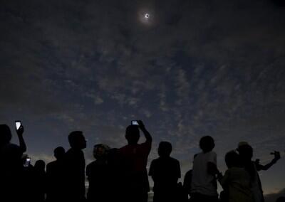 People watch and take pictures of the solar eclipse at the beach on Ternate island, Indonesia, March 9, 2016.  REUTERS/Beawiharta