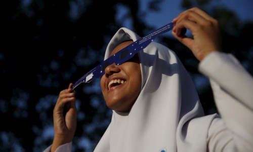 A school girl watches a partial solar eclipse at the Planetarium in Kuala Lumpur, Malaysia, March 9, 2016. REUTERS/Olivia Harris