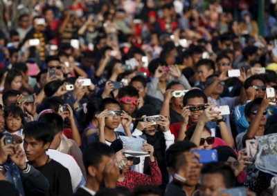 People watch a solar eclipse near the Ampera Bridge along the banks of the Musi River in Palembang, South Sumatra province, Indonesia March 9, 2016. REUTERS/Darren Whiteside