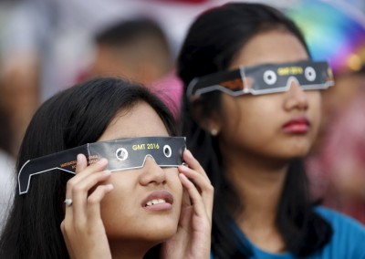 People watch a solar eclipse near the Ampera Bridge along the banks of the Musi River in Palembang, South Sumatra province, Indonesia March 9, 2016. REUTERS/Darren Whiteside