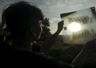 A person uses a medical X-ray film to view the sun during a solar eclipse in Silaut,  West Sumatra province, Indonesia March 9, 2016 in this photo taken by Antara Foto. REUTERS/Iggoy el Fitra/Antara Foto