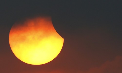 A partial solar eclipse is seen through clouds in Bangkok, Thailand, March 9, 2016. REUTERS/Athit Perawongmetha