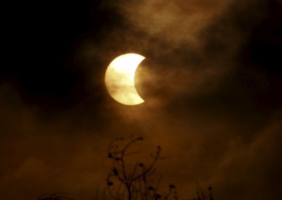 A partial solar eclipse is seen through clouds in Bangkok, Thailand, March 9, 2016. REUTERS/Chaiwat Subprasom