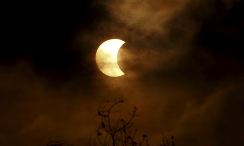 A partial solar eclipse is seen through clouds in Bangkok, Thailand, March 9, 2016. REUTERS/Chaiwat Subprasom