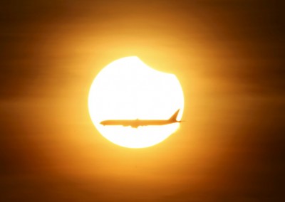 An aeroplane flies past the sun as it goes into a partial solar eclipse in Singapore March 9, 2016. REUTERS/Edgar Su