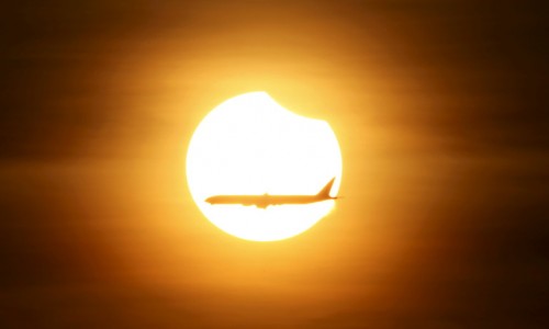 An aeroplane flies past the sun as it goes into a partial solar eclipse in Singapore March 9, 2016. REUTERS/Edgar Su