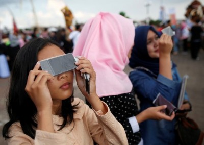 People test filters for watching a solar eclipse near the Ampera Bridge on the Musi River the day before thousands of people are expected to gather to witness the event in Palembang, South Sumatra province, Indonesia March 8, 2016. REUTERS/Darren Whiteside