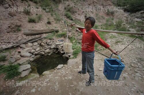 A local resident, Guan Wangying, collects water from a spring deep into the valley near her village of Houjialiang. Guan's family had always depended on corn for their livelihood, but drops in groundwater due to coal mining has resulted in serious water shortages which in turns lead to less corn production.