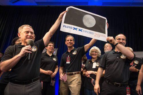 New Horizons Principal Investigator Alan Stern of Southwest Research Institute (SwRI), Boulder, CO., left, Johns Hopkins University Applied Physics Laboratory (APL) Director Ralph Semmel, center, and New Horizons Co-Investigator Will Grundy Lowell Observatory hold a print of an U.S. stamp with their suggested update since the New Horizons spacecraft has explored Pluto,  Tuesday, July 14, 2015 at the Johns Hopkins University Applied Physics Laboratory (APL) in Laurel, Maryland. Photo Credit: (NASA/Bill Ingalls)