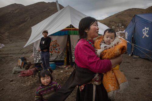 A Tibetan woman holds a baby as she stands outside a tent at a temporary camp for cordycep pickers near Zadoi in the Yushu Tibetan Autonomous PrefectureKevin Frayer/Getty Images