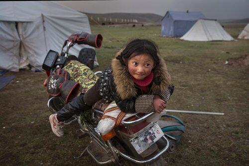 A young Tibetan nomad girl rests on a motorcycle at a temporary camp for cordycep fungus pickers near SershulKevin Frayer/Getty Images