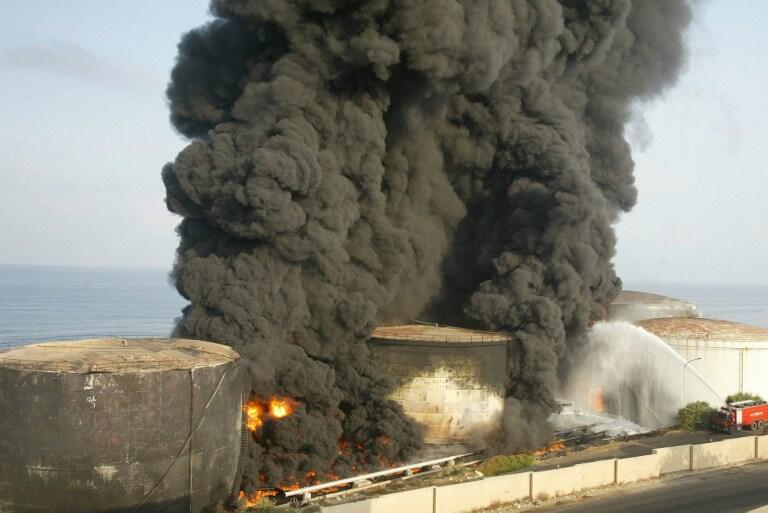 Petrol tanks are seen on fire at the al-Jieh Electricity station following an Israeli air strike in Jieh 15 kms south of Beirut 16 July 2006. The death toll from Israel's five-day-old offensive against Lebanon topped 100 Sunday following the death of a civilian in an air raid near the southern port of Tyre. AFP PHOTO/MAHMOUD ZAYAT / AFP PHOTO / MAHMOUD ZAYYAT