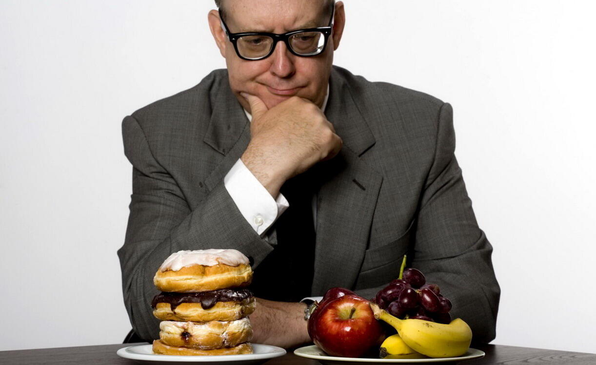 Man contemplating eating healthy or unhealthy food, studio shot