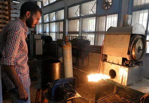 Engineering student, Mohamed Amr works near flame used in the process of burning car tires into diesel in Cairo