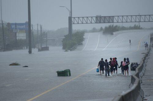 Evacuation residents from the Meyerland area walk onto an I-610 overpass for further help during the aftermath of Hurricane Harvey August 27, 2017 in Houston, Texas. Hurricane Harvey left a trail of devastation Saturday after the most powerful storm to hit the US mainland in over a decade slammed into Texas, destroying homes, severing power supplies and forcing tens of thousands of residents to flee. / AFP PHOTO / Brendan Smialowski